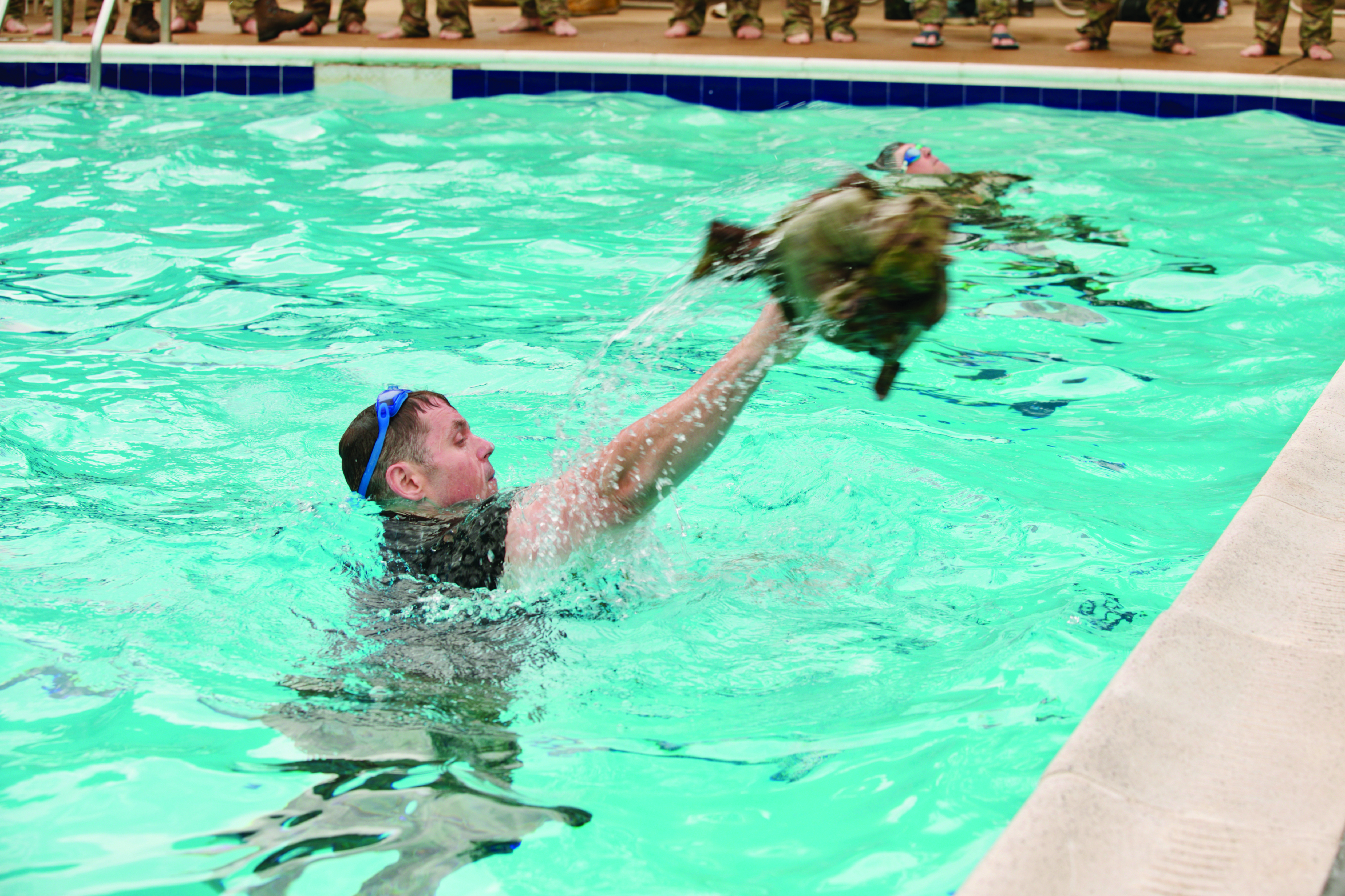 U.S. Army Reserve CPT John Cooper, a judge advocate assigned to the Military Intelligence Readiness Command, doffs his uniform in the pool during a German Armed Forces Badge event that the Defense Attaché staff of the Federal Republic of Germany officiated and the 3d Infantry Regiment (The Old Guard) hosted on Joint Base Myer-Henderson Hall, VA. The German Armed Forces Proficiency Badge is a German military award similar to the U.S. Army’s Expert Soldier Badge and consists of knowledge and skills-based tasks, a physical fitness test, pistol marksmanship, a swim event, and a ruck march. (Credit: MAJ Joshua Frye)